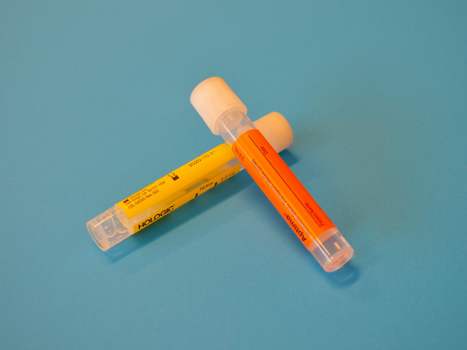 Two medical specimen transport tubes on a blue surface, with no people